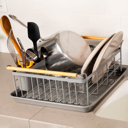A large Yamazaki dish rack with water contained in its drip tray and dishes held above, dry, out of the water. 